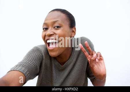 Porträt von lächelnden jungen Afrikanerin machen Friedenszeichen Selfie vor weißem Hintergrund Stockfoto