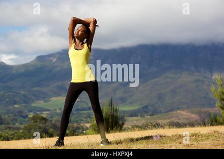 In voller Länge Portrait von Fit junge Afrikanerin stehen und streckte Arme Stockfoto