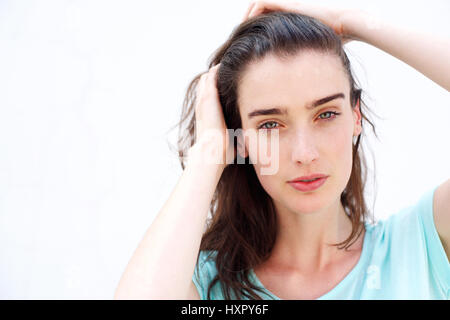 Porträt einer jungen attraktiven Frau läuft ihren Händen durch ihr Haar hautnah Stockfoto