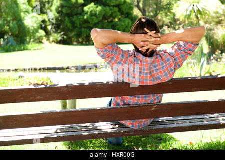 Porträt von hinten junge männliche entspannend auf Holzbank im park Stockfoto