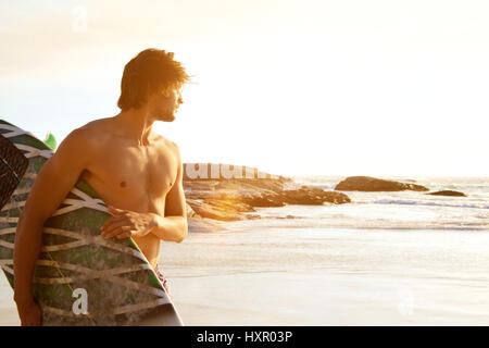 Seite Porträt der jungen Surfer stehen bei Sonnenuntergang Stockfoto
