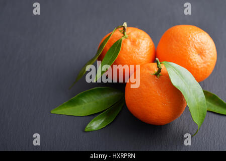 Mandarinen mit Blättern auf Schiefer Hintergrund closeup Stockfoto
