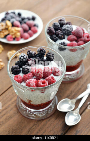 Pudding mit Chia-Samen, Joghurt und gefrorene Beeren im Glas Stockfoto