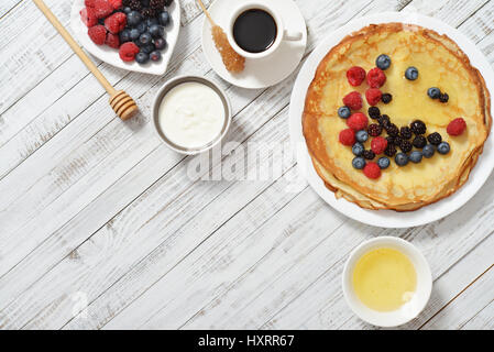 Pfannkuchen mit frischen Beeren und Honig auf hölzernen Hintergrund Stockfoto