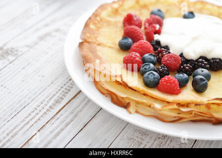 Pfannkuchen mit frischen Beeren und Sauerrahm auf hölzernen Hintergrund Stockfoto