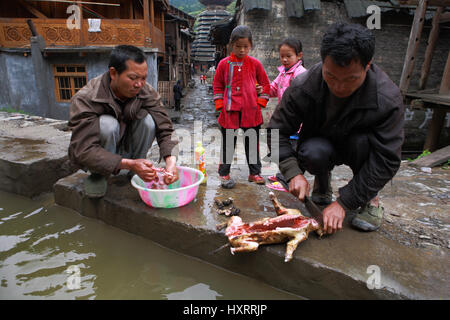 Zengchong Dorf, Guizhou, China - 13. April 2010: chinesische Männer Bauern Bauern Schlachten Hund in der Nähe von einem ländlichen Fluss, vor zehn Jahren zwei Mädchen Z Stockfoto