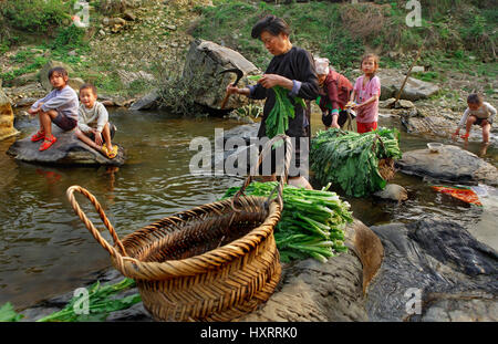 Zengchong Dorf, Guizhou, China - 11. April 2010: asiatische Familie, zwei Frauen und vier Kinder sind in der Mitte des Flusses Dorf, Erwachsene Chinesisch w Stockfoto