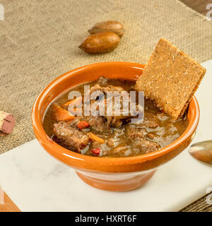 Ein quadratischer Foto ein Fleisch-und Gemüseeintopf in ein Steingut-Schüssel mit einem Fladenbrot und einem Weinkorken Stockfoto