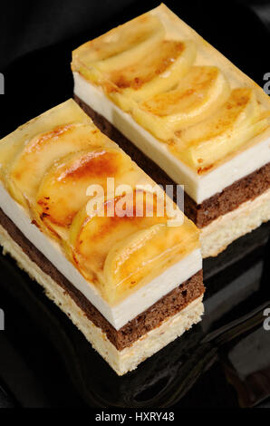 Kuchen aus Karamell, Apfel Mousse, Schokolade und Mandeln Biskuit mit einer Schicht Gelee karamellisiertem Apfel Scheiben gestapelt Stockfoto