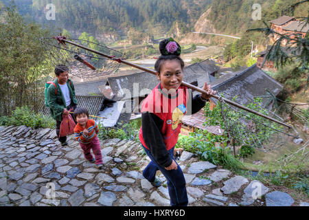 Langde Dorf, Guizhou, China - 15. April 2010: Frau Bauer mit einer Rose im Haar Langde Miao Dorf ländlichen Stoun unterwegs ist. Stockfoto