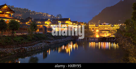 Xijiang Miao Dorf, Provinz Guizhou, China - 18. April 2010: große Miao ethnische Minderheit Dorf bei Nacht beleuchtet Holzbauten sind Refle Stockfoto