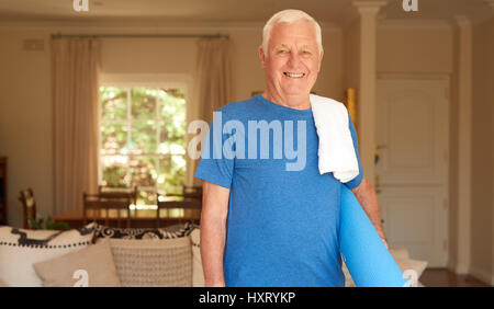Aktive älterer Mann zu Hause bereit, Yoga zu tun Stockfoto