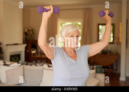 Fit und aktiv senior Frau Aufhebung Hanteln zu Hause Stockfoto