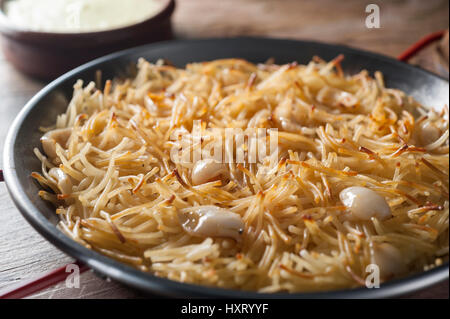 Nudeln mit gebratenen Baby Tintenfisch mit Alioli-Sauce. Typische Seamans spanischen Gericht in einer Metall-Pfanne Stockfoto