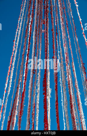 Leuchtend bunte rot und weiß Girlande Girlanden flattern im Wind gegen blauen Himmel Stockfoto