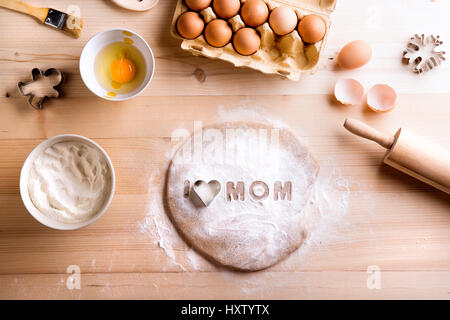 Mütter Tag Zusammensetzung. Backen, Zutaten und Küchengeräte auf Tisch gelegt. Ich liebe Mama Zeichen von Mehl und Cookie Cutter. Studio am hölzernen erschossen Stockfoto