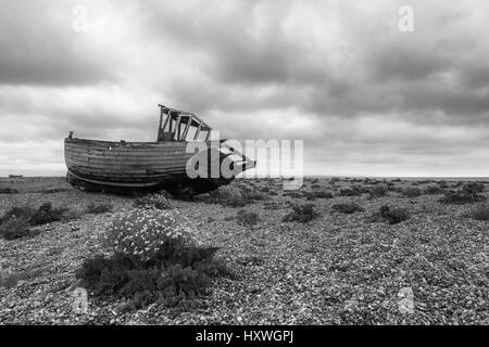 Fischerboot auf dem Schindelstrand in Dungeness, Kent, England, Großbritannien, aufgegeben. Schwarzweiß-Version Stockfoto