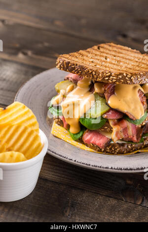 Große hausgemachte Sandwich mit Roastbeef, Speck, Gurken, Baby-Spinat und Krautsalat Dressing in geröstetem Brot Stockfoto