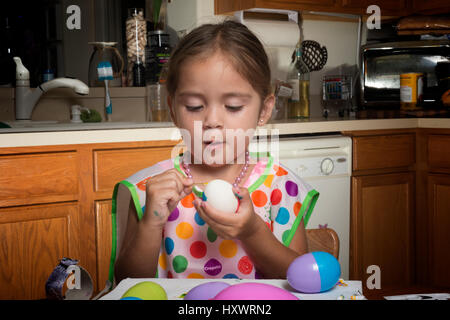 junges Mädchen am Tisch Ostereier färben Stockfoto