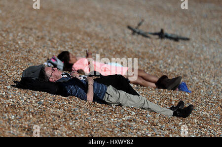 Menschen genießen Sie die Sonne am Strand in Hastings, East Sussex, an einem Tag bei Temperaturen im Südosten von England erwartet wurden, um saisonale überdurchschnittlich hoch und erreichen 22 C. Stockfoto