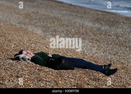 Eine Dame genießt die Sonne am Strand in Hastings, East Sussex, an einem Tag bei Temperaturen im Südosten von England erwartet wurden, um saisonale überdurchschnittlich hoch und erreichen 22 C. Stockfoto