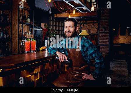 Porträt der Barmann Hipster mit Bart lächelnd sitzt in Bar. Stockfoto