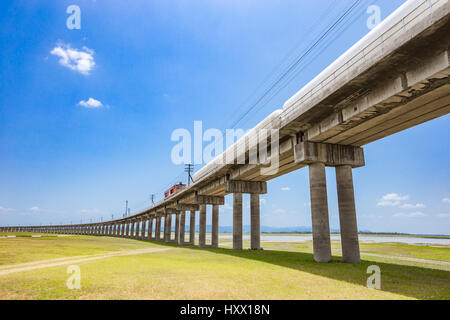 Railroad tracks mit Güterzug vorbei an den Stausee, Pa Sak Jolasid Dam, Lopburi Thailand. Stockfoto