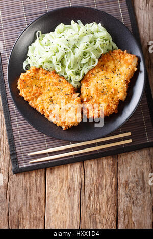 Japanische Küche: Hähnchen Schnitzel in Paniermehl Panko und Nudeln mit grünem Tee Macha auf dem Tisch. Vertikale Ansicht von oben Stockfoto