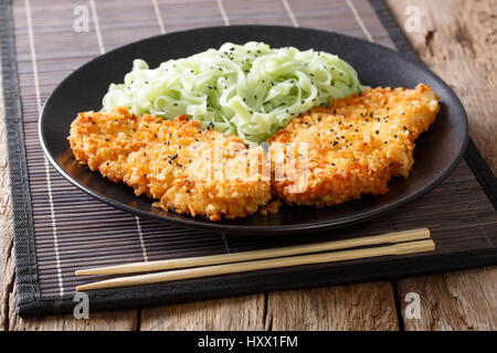 Hähnchen Schnitzel in Paniermehl und grüne Nudeln mit Sesam-close-up auf dem Tisch. horizontale Stockfoto