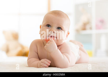 Baby-Kleinkind beißt Beißring auf Bett weared Windel liegend Stockfoto