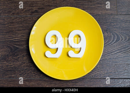 Die Nummer 99 auf die gelbe Platte und braunen Hintergrund. Stockfoto