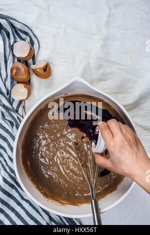 Eine Frau hinzufügen rote Lebensmittelfarbe in einem Kuchenteig aus Draufsicht fotografiert. Stockfoto