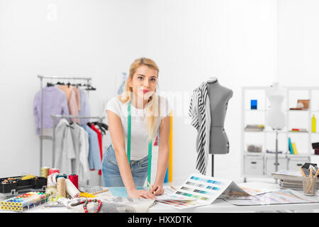 junge Mode-Designer lächelnd und stand vor dem Schreibtisch in der Werkstatt Stockfoto