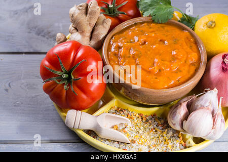 Schüssel mit pflanzlichen Tikka Masala Sauce und Zutaten, die eingehen, so dass es - rote Tomaten, Paprika, Karotten, Koriander Blätter, Zwiebel, Knoblauch, Juwel Stockfoto