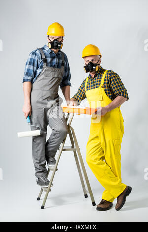 Zwei Arbeiter in Schutzkleidung mit Farbroller und Farbe Stockfoto