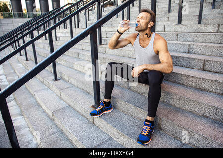 Durstige Sportler nehmen Sie einen Rest und Trinkwasser nach dem laufen. Fitness, Sport, Training und Menschen gesunden Lifestyle-Konzept. Stockfoto