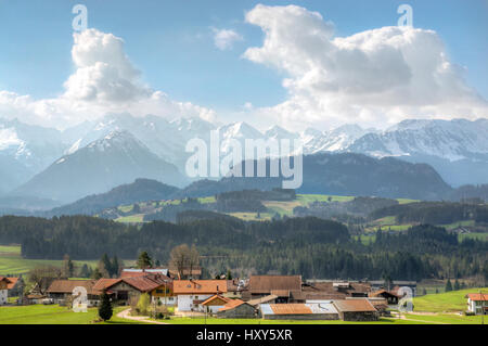 Dorf, umgeben von grünen Wäldern und schneebedeckten Bergen Stockfoto