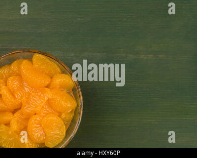 Mandarine Segmente in einer Schüssel vor einem grünen Hintergrund Stockfoto