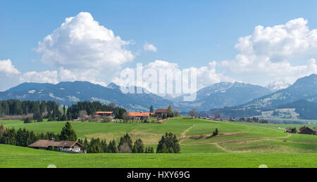 Dorf, umgeben von grünen Wäldern und schneebedeckten Bergen Stockfoto