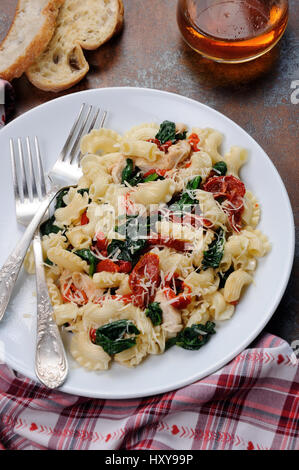 Warmer Salat Nudeln mit Huhn, Sonne getrocknet, Tomaten, Spinat, Paprika und aromatisierte Parmesan-Käse Stockfoto