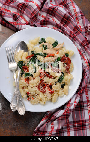 Warmer Salat Nudeln mit Huhn, Sonne getrocknet, Tomaten, Spinat, Paprika und aromatisierte Parmesan-Käse Stockfoto