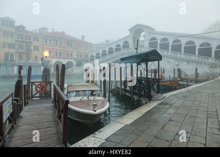 Nebligen Morgen am Canal Grande in Venedig, Italien. Rialto-Brücke ragt im Hintergrund. Stockfoto