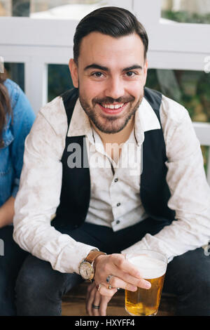 Porträt eine attraktive stilvolle junge Mann trinkt Bier in einer Bar mit Freunden Stockfoto