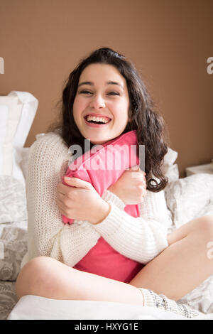 Glückliche junge Frau im Bett lachen Stockfoto