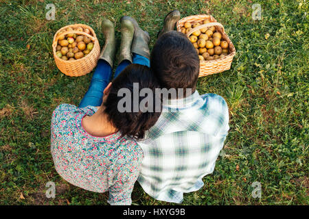 Liebespaar sitzen auf dem Rasen im Herbst nach der Ernte der Äpfel. Ansicht von oben Stockfoto