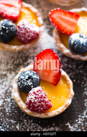 Kleine Törtchen von Sahne und frischen Beeren mit Puderzucker Stockfoto