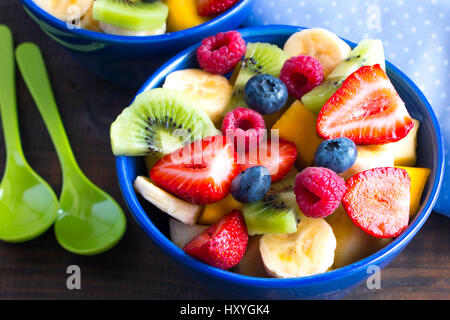 Bunt und vielfältig Obstsalat in blauen Schalen auf rustikalen Holztisch Stockfoto