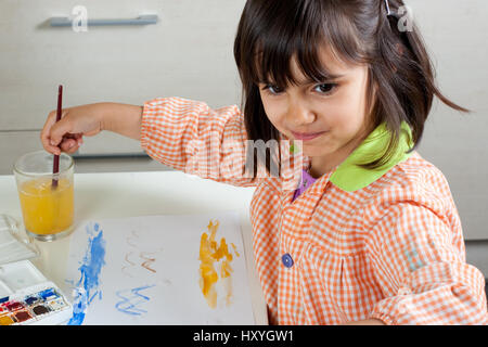 Fröhliches kleines Mädchen malen mit Wasserfarben Stockfoto