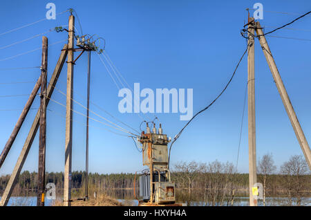 Strom versorgen Stromleitungen aus lokalen Umspannwerk, verbunden mit einem Verteilung Transformator im Frühling Landschaft. Stockfoto