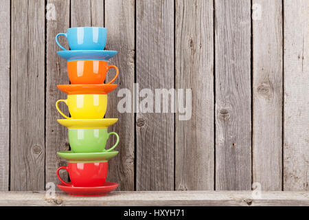 Farbenfrohe Kaffeetassen auf Regal gegen rustikale Holzwand mit Textfreiraum Stockfoto